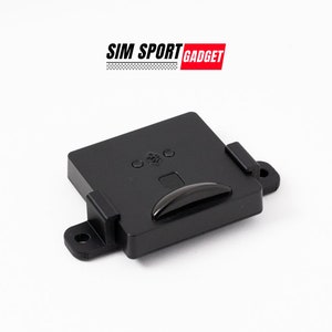 Peut inclure: Un dispositif en plastique noir avec un petit bouton rectangulaire et une fente pour une carte. L'appareil possède deux petites languettes sur le côté pour le montage.