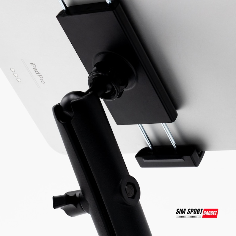 May include: A black tablet holder with a ball joint and adjustable arm. The holder is attached to a white tablet, with the text "iPad Pro" visible. The holder is designed to securely hold a tablet.