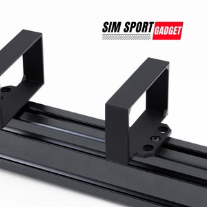 Puede incluir: Soportes y rieles de metal negro. Los soportes son rectangulares con un centro hueco y se fijan a los rieles con tornillos. El texto "SIM SPORT GADGET" está en la esquina superior derecha.