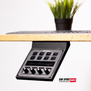 May include: A black control panel with buttons and knobs mounted under a wooden desk. The panel has the text "SIM SPORT GADGET" printed on the bottom right corner.