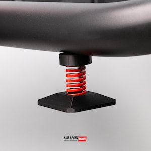 May include: Close-up of a black component with a red spring and a square base. The component is part of a larger structure, possibly a gaming or sports equipment. The logo "SIM SPORT GADGET" is visible at the bottom.