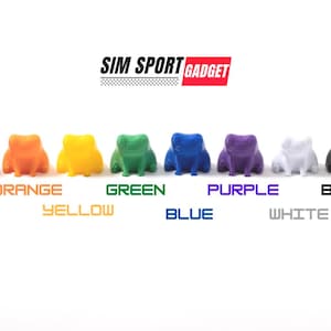 Puede incluir: Ocho figuras de ranas de colores: rojo, naranja, amarillo, verde, azul, morado, blanco y negro. El texto "SIM SPORT GADGET" aparece encima de las ranas, con el nombre de cada color debajo.
