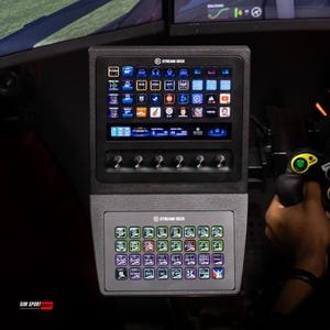 Puede incluir: Un panel de control Stream Deck negro con múltiples botones iluminados y una pantalla que muestra varios iconos de aplicaciones. El panel tiene una sección inferior con botones adicionales.