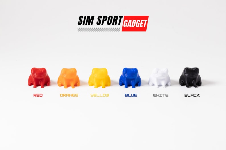 Pode incluir: Seis pequenas figuras de sapo em diferentes cores: vermelho, laranja, amarelo, azul, branco e preto. As figuras est&atilde;o dispostas em uma fileira sobre uma superf&iacute;cie branca. O texto "SIM SPORT GADGET" &eacute; exibido acima das figuras.