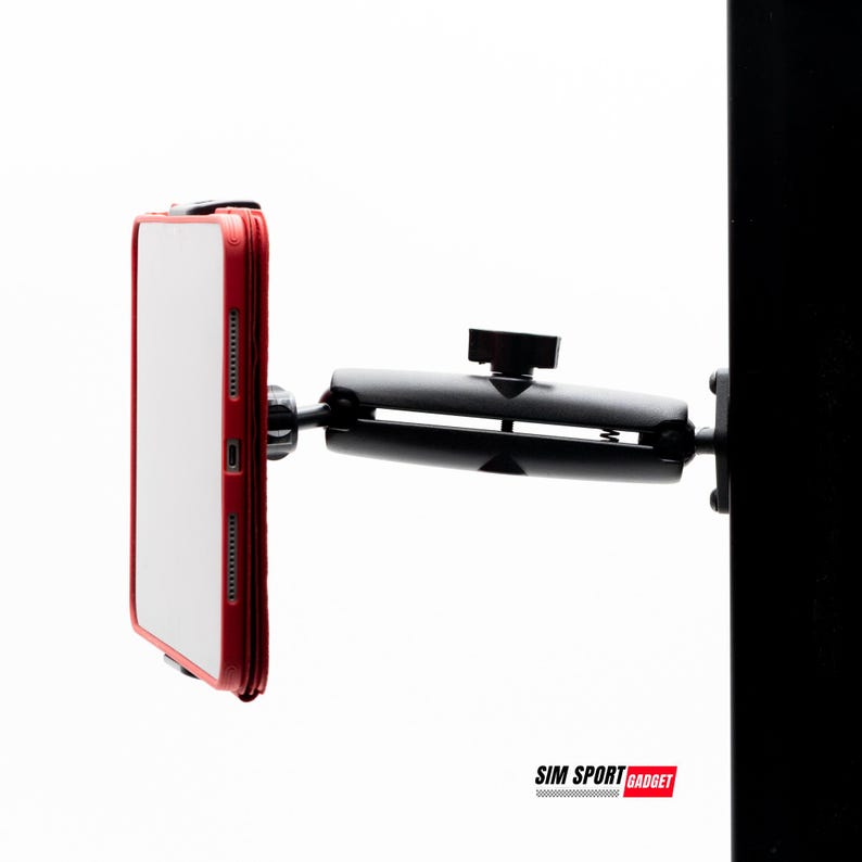 May include: A black phone mount with a red-framed phone attached. The mount is connected to a black vertical surface. The phone is white with a red border. The text "SIM SPORT GADGET" is at the bottom.