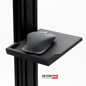 Könnte beinhalten: Ein schwarzer Metallständer mit einem schwarzen Mauspad und einer grauen Maus darauf. Der Ständer trägt ein Etikett mit der Aufschrift "SIM SPORT GADGET".