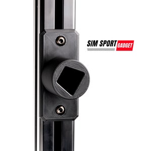 Op de afbeelding: Zwarte metalen beugel met een vierkant gat, bevestigd aan een zwart metalen rail. De beugel heeft twee kleine schroeven aan de voorkant. De tekst "SIM SPORT GADGET" is zichtbaar op de achtergrond.