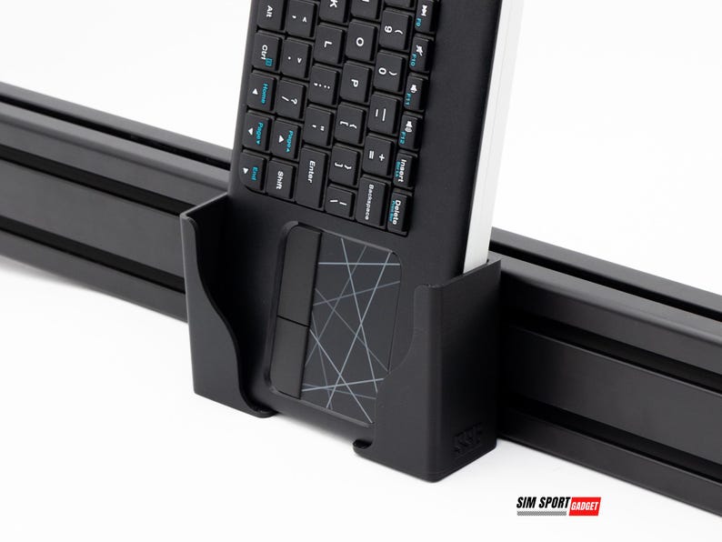 Puede incluir: Un teclado negro con un panel t&aacute;ctil integrado se sujeta en un soporte negro. El teclado tiene una distribuci&oacute;n QWERTY est&aacute;ndar con letras blancas en las teclas. El panel t&aacute;ctil tiene un dise&ntilde;o geom&eacute;trico. El soporte est&aacute; montado en un riel negro.