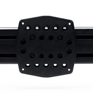 May include: A black, textured mounting plate with multiple holes and a curved shape, attached to a black metal rail. The plate has a series of circular and oblong holes. The background is white.