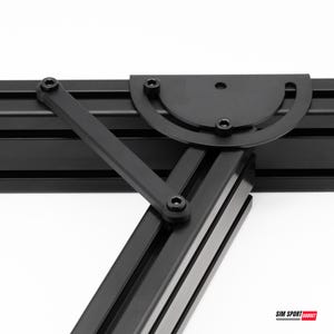 Puede incluir: Un marco de perfil de aluminio negro con un soporte de ajuste metálico semicircular con una ranura en arco y un brazo de soporte diagonal. El conjunto está asegurado con pernos hexagonales negros. El texto SIM SPORT GADGET es visible.