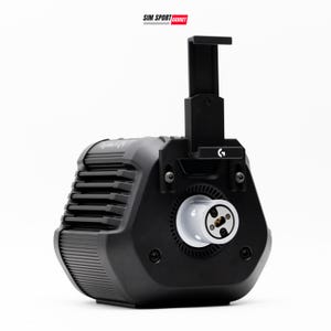 May include: A black Logitech racing wheel base featuring a vertical mounting bracket with a G logo, a central white circular shaft connector, and horizontal cooling vents on the side. The text SIM SPORT GADGET is printed at the top of the frame.