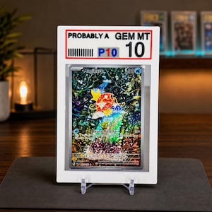 May include: A graded Magikarp trading card encased in a white plastic slab. The card features a colorful illustration of a red fish leaping from water against a dark, detailed background. The label at the top reads PROBABLY A GEM MT 10.