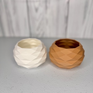 May include: Two geometric ceramic planters, one white and one brown. The planters have a unique, faceted design.