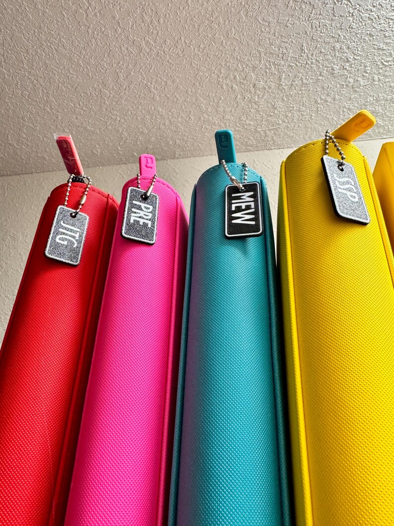 May include: Five colorful zippered pouches with silver keychains and tags that say "JTG", "PRE", "NEW", "SSP".