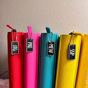 May include: Four colorful zipper binders with black labels that say "JTG", "PRE", "MEW", and "SSP".