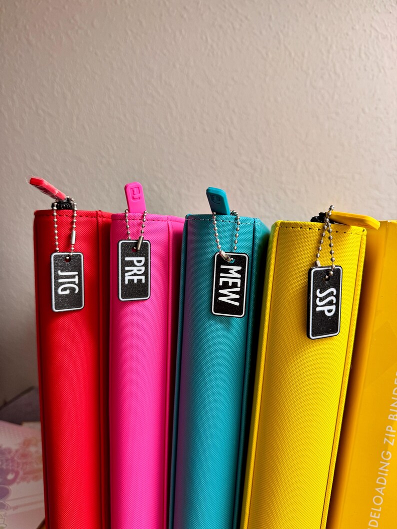 May include: Four colorful zipper binders with black labels that say "JTG", "PRE", "MEW", and "SSP".