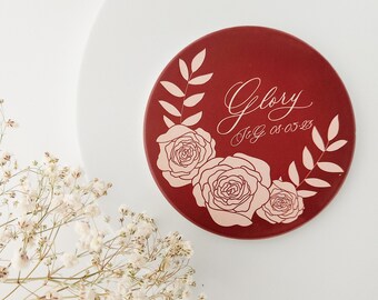 Könnte beinhalten: Ein runder Untersetzer in Rot mit einem floralen Design und dem Text "Glory" in Kursivschrift. Der Text "J & G 05.05.23" ist ebenfalls enthalten.