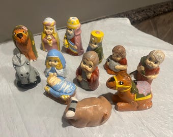 May include: A collection of hand-painted ceramic nativity figurines. The set includes figures of the baby Jesus, Mary, Joseph, the three wise men, animals, and other characters. The figurines are painted in various colors.
