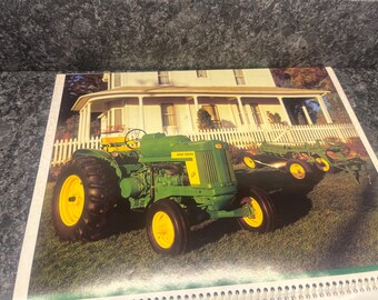 May include: A green John Deere tractor with a yellow wheel and a plow attached to the back. The tractor is parked in front of a white house with a porch.