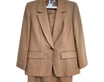 May include: A tan blazer and skirt suit. The blazer has a single button closure and two pockets. The skirt is knee-length.