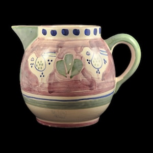 May include: A ceramic pitcher with a green handle and a pink, white, and blue floral design. The pitcher features two birds and a green leaf design.