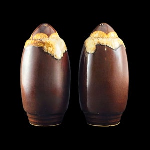 Puede incluir: Un par de saleros y pimenteros de cerámica marrón con un diseño de glaseado blanco. Los saleros tienen forma de huevo y tienen un acabado brillante.