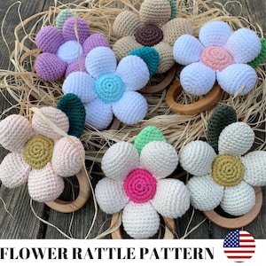 Op de afbeelding: Een set gehaakte bloemenrammelaars met houten ringen. De bloemen zijn in verschillende kleuren, waaronder roze, wit, groen, bruin en geel. De bloemen zijn bevestigd aan houten ringen.