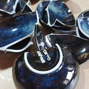 Puede incluir: Un juego de cuencos de cer&aacute;mica azul y blanca rotos con un borde blanco. Los cuencos tienen un esmalte moteado y est&aacute;n dispuestos en una pila.
