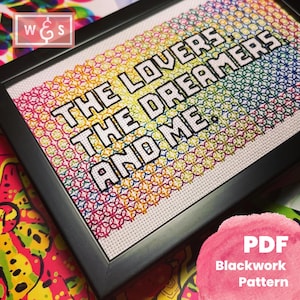 May include: A framed cross-stitch pattern with a rainbow background and the text "THE LOVERS THE DREAMERS AND ME."