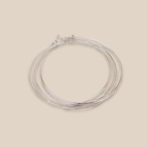 Peut inclure: Un ensemble de quatre boucles d'oreilles créoles en argent. Les créoles sont empilées les unes sur les autres.