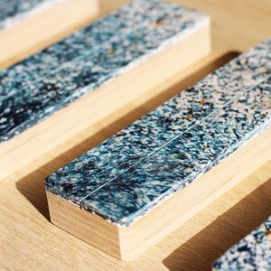 Peut inclure: Gros plan sur plusieurs blocs rectangulaires en bois avec une surface mouchetée bleue et blanche. Les blocs sont disposés sur une surface en bois clair, le motif bleu et blanc créant un aspect texturé. Les blocs ont une base en bois naturel.