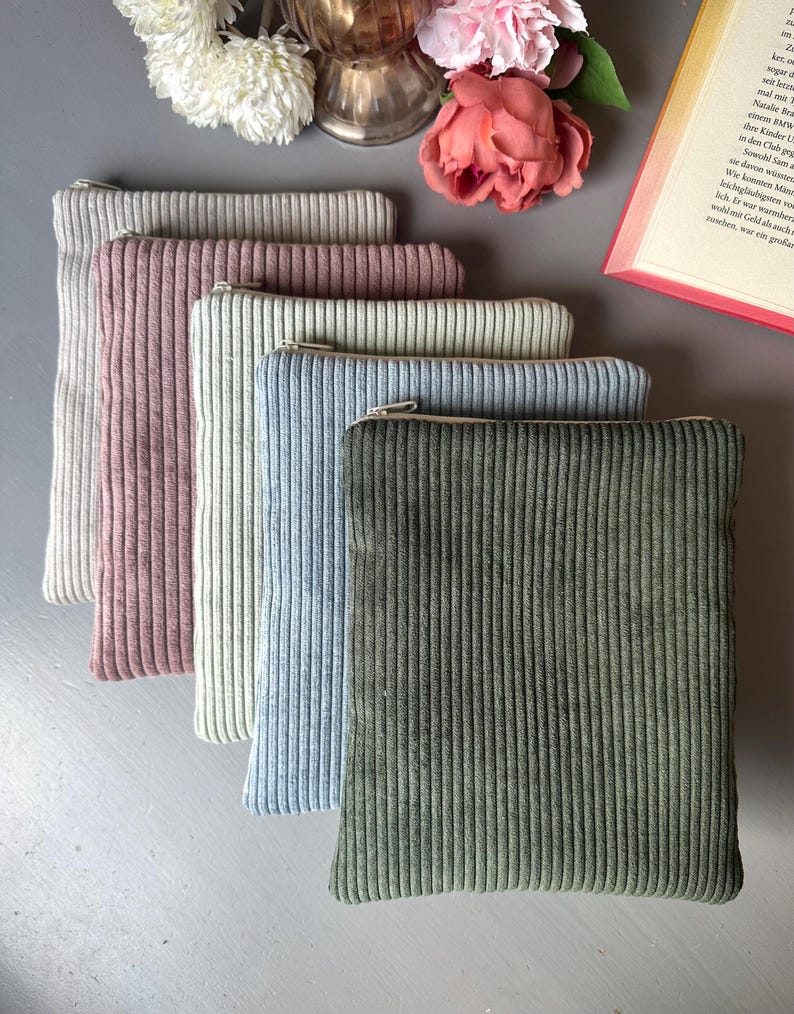 May include: Five zippered pouches in different colors, including beige, pink, blue, and green. The pouches are made of a soft, textured fabric and have a ribbed design.