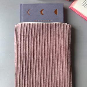以下が含まれることがあります： ピンクのコーデュロイのジッパー付きポーチの中にグレーのジャーナルが入っています。ジャーナルには月のデザインと「666 JOURNAL」の文字があります。