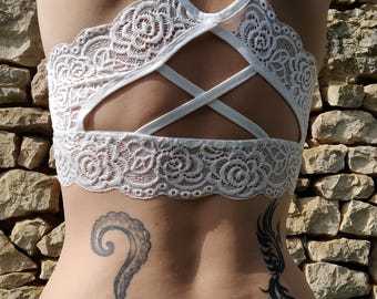 May include: A woman with a white lace bralette and blue jeans. She has a tattoo of an octopus on her lower back and a tattoo of a bird on her right hip.