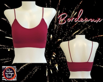 May include: A burgundy-colored sports bra with thin straps. The bra is made of a soft, stretchy material and has a seamless design.