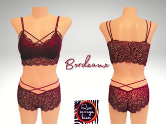 May include: A burgundy lace lingerie set with a criss-cross strap design on the bra and matching panties. The set features a floral lace pattern and a delicate trim.