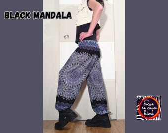 May include: A person wearing black pants with a blue and white mandala pattern. The pants are loose fitting and have a wide leg. The person is standing in front of a white wall. The text "BLACK MANDALA" is visible at the top of the image.