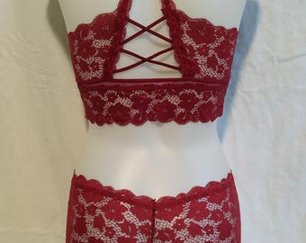 May include: A red lace lingerie set with a criss-cross back detail on the bra. The set features a floral pattern.