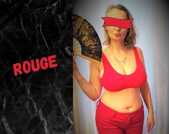 May include: A woman wearing a red bra and red pants holds a black and gold fan. The word "ROUGE" is written in red on a black background.