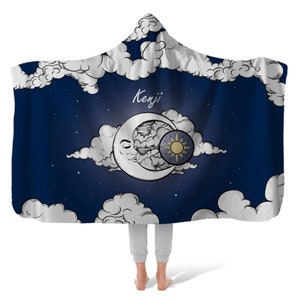 May include: A blue hooded blanket with a crescent moon and sun design. The blanket has the name "Kenji" written on it.