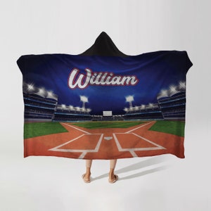 May include: A blue and green hooded blanket with a baseball stadium scene and the name "William" in red and white lettering.