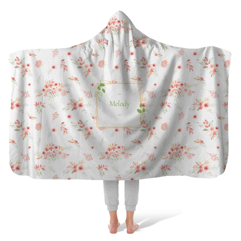 May include: A white hooded blanket with a floral pattern and a gold frame with the name "Melody" in green text.
