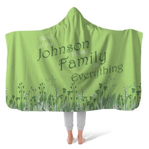 May include: Green hooded blanket with a floral border and the text "Here at the Johnson Home Family is Everything".