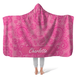 Puede incluir: Manta de capucha rosa con un patr&oacute;n de paisley y el nombre "Charlotte" bordado en la parte delantera.
