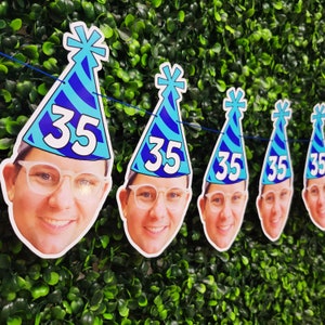May include: A birthday banner with blue and white party hats featuring the number 35 and faces of people.