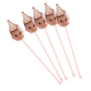 May include: Five pink and white striped straws with a photo of a baby's face on each end. The photos are of a baby wearing a pink and white party hat.