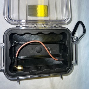 May include: A clear plastic case with a black foam interior. A brown coaxial cable with a gold connector is visible inside the case.