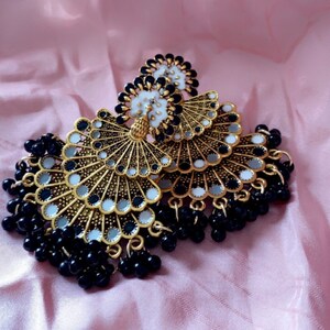 May include: A pair of gold tone earrings with black and white mirrored accents and black bead fringe.
