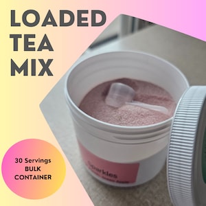 Puede incluir: Un recipiente de pl&aacute;stico blanco con polvo rosa en su interior. El recipiente tiene una cuchara y una tapa. La etiqueta del recipiente dice "Sparkles" y "Loaded Tea Mix". El recipiente est&aacute; etiquetado como un recipiente a granel de 30 porciones.