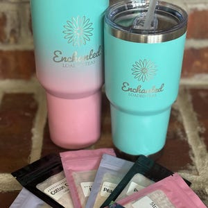 Puede incluir: Dos vasos de acero inoxidable turquesa y rosa con tapas y pajitas. Los vasos tienen el logotipo "Enchanted Loaded Teas" y un dise&ntilde;o de flores. Hay seis peque&ntilde;as bolsas de mezcla de t&eacute; con diferentes sabores, incluyendo "Strawberry Daiquiri" y "Cotton Candy".
